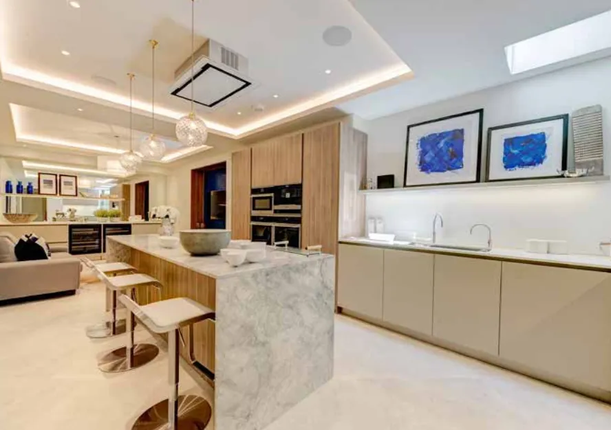 Kitchen with a marble-topped island, bar stools and recessed ceiling lights