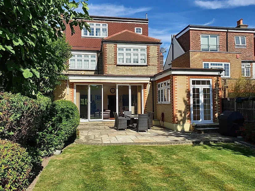 Rear of a brick house with a single-storey extension, glazed doors and a lawn
