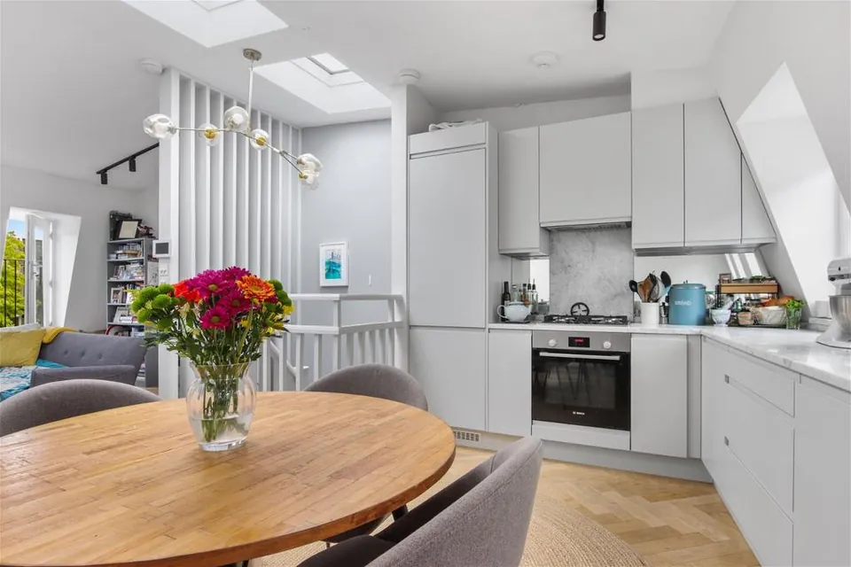 Grey kitchen and round dining table under roof lights