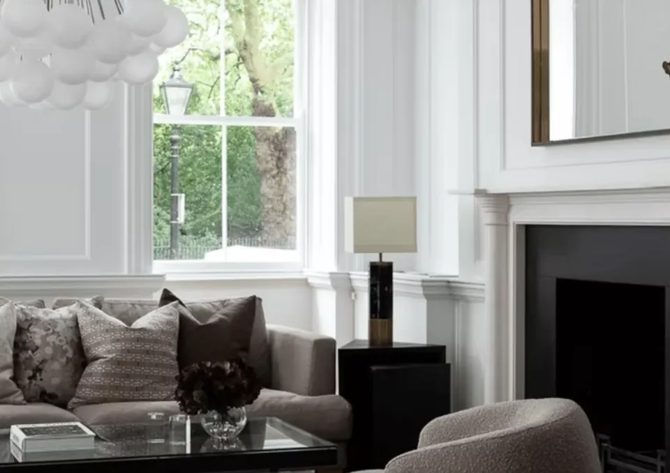 Living room with a sofa, armchair and a black fireplace below a large mirror