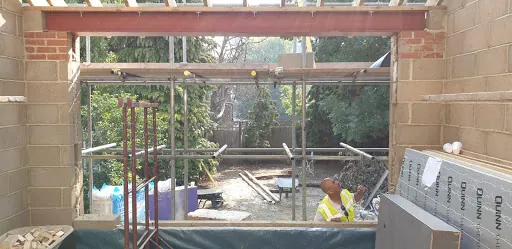 Building site with a new steel beam spanning a wide opening in blockwork
