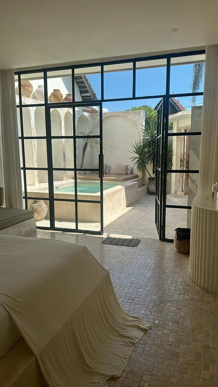 Guest room with steel-framed glazing opening onto a courtyard plunge pool