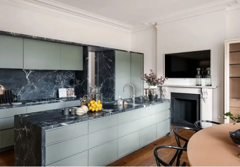 Kitchen with sage-green cabinets and dark marble worktops